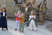 Alcuni bambini reggono bandierine accanto a un carro carico di fieno