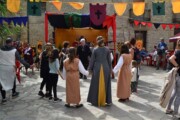 Un gruppo balla in girotondo accanto a un banco festivo