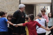 Il vescovo forma un girotondo con i bambini sotto un arco