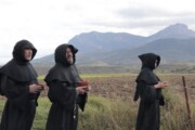 Tre frati camminano per la campagna con i Pirenei aragonesi sullo sfondo