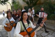 Una musicista suona la chitarra camminando per le vie di Bailo