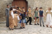 Bambini e adolescenti giocano in girotondo davanti a una porta antica