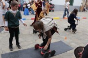 Alcuni bambini giocano con un monopattino di legno al mercato medievale